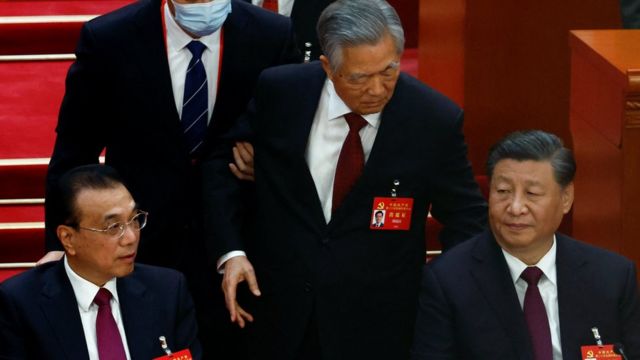 Former Chinese president Hu Jintao leaves his seat next to Chinese President Xi Jinping and Premier Li Keqiang, during the closing ceremony of the 20th National Congress of the Communist Party of China