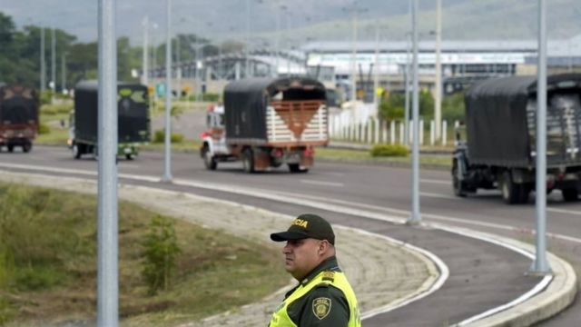 Caminhões com ajuda humanitária passam por um policial colombiano na ponte Tienditas, na fronteira entre a Colômbia e a Venezuela. Foto: 7 de fevereiro de 2019