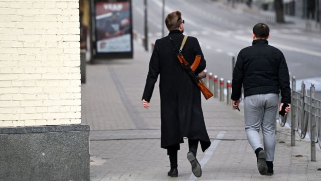 A man carrying a Kalashnikov AK-47 rifle walks in central Kyiv on February 25, 2022