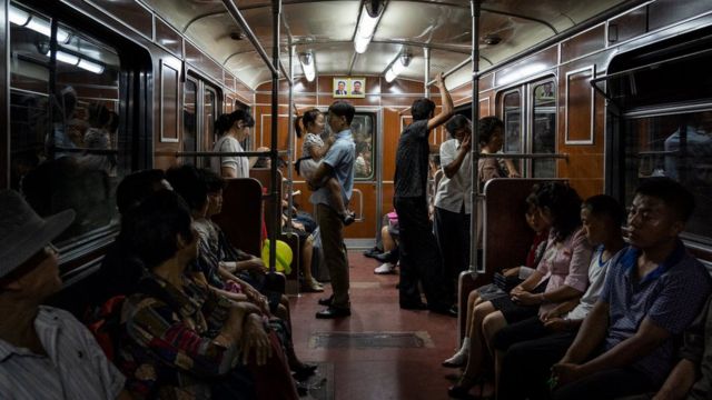 (캡션) 평양 지하철에서 아이를 안고 있는 아빠. 객차 뒤편에 김일성-김정일 사진이 걸려있다