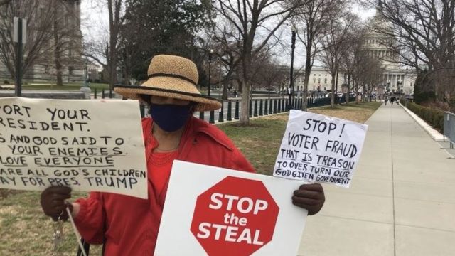 Senhora segurando vários cartazes em via de pedestres em Washington