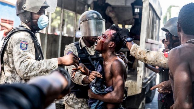 Hombre herido y militares en Haití