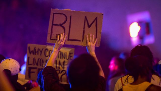 Persona sosteniendo un letrero que dice BLM, por Black Lives Matter