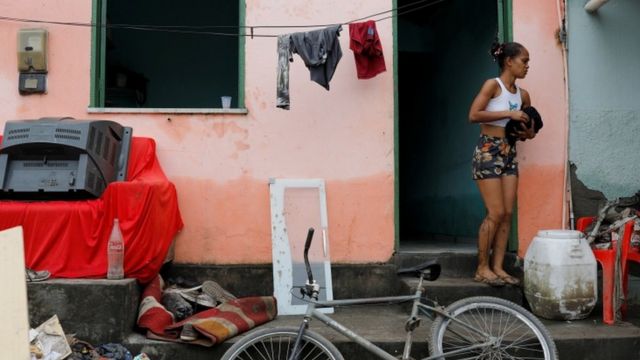 Foto de una mujer frente a su casa afectada por las inundaciones en Brasil