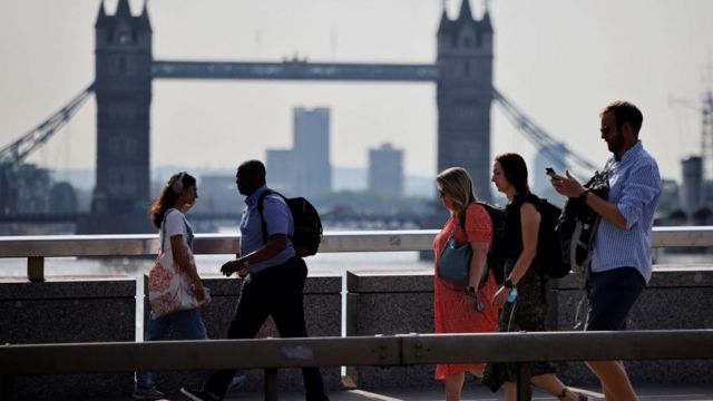 Personas caminando con el Puente de la Torre de Londres al fondo.