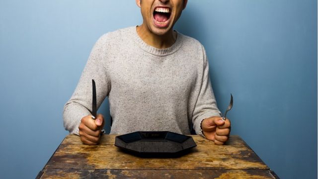 Hungry man sits at a table with plate, knife and fork