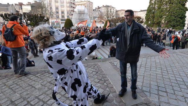 Mauricio García abraza a un activista disfrazado de vaca.