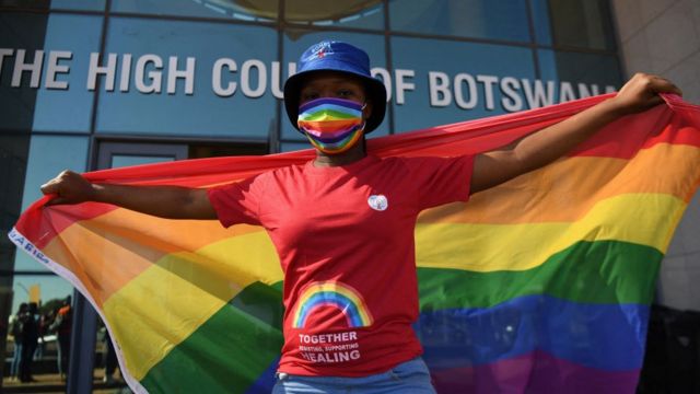 Woman with rainbow flag in front of a Botswana court.