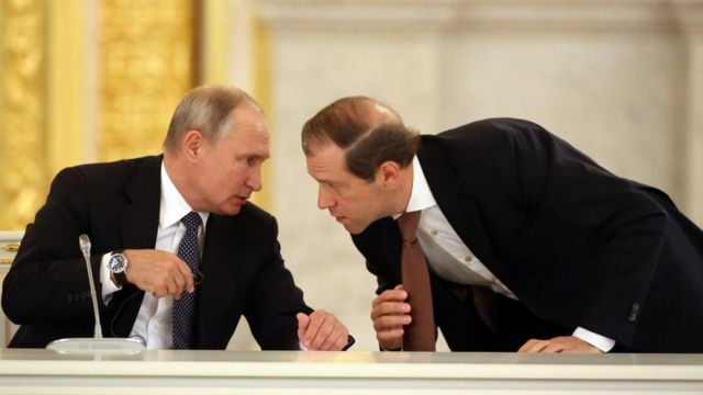 الرئيس الروسي فلاديمير بوتين (إلى اليسار) يتحدث إلى وزير الصناعة والتجارة دينيس مانتوروف (يمين) خلال اجتماع روسي إيطالي في الكرملين في 24 أكتوبر/تشرين أول 2018 في موسكو