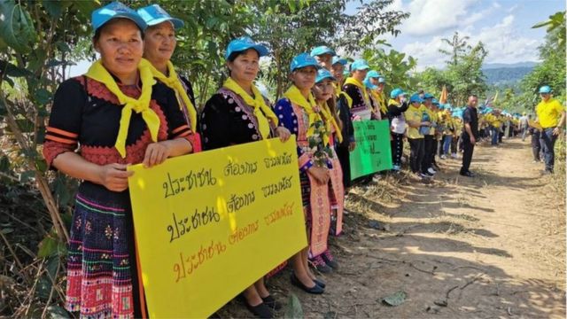 ประชาชนที่อยู่ในชุด "จิตอาสา" ชูป้ายให้กำลังใจ ร.อ. ธรรมนัส ระหว่างเป็นประธานพิธีเปิดโครงการ "จิตอาสาสืบสานการสร้างป่าและเกษตรกรรมยั่งยืน ในเขตปฏิรูปที่ดินเฉลิมพระเกียรติในโอกาสมหามงคลพระราชพิธีบรมราชาภิเษกฯ" และมอบเอกสารสิทธิ ส.ป.ก. 4-01 ให้เกษตรกรชาวพะเยา เมื่อวันที่ 15 ก.ย. 2562