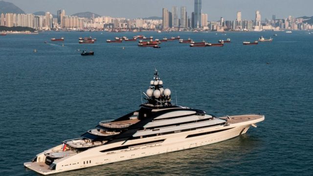 Le superyacht Nord amarré dans les eaux de Hong Kong avec l'horizon de la ville en arrière-plan.