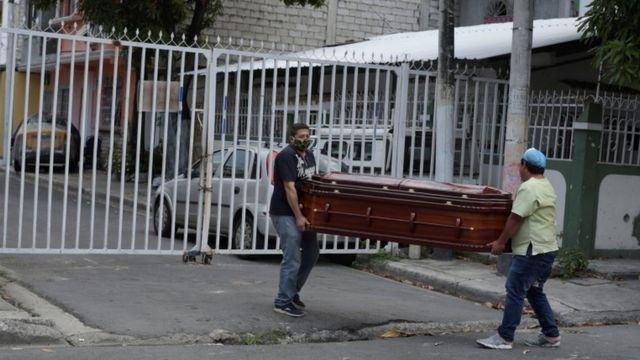 Dois homens carregam um caixão pelas ruas de Guayaquil.