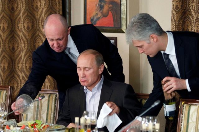 صورة ملتقطة في نوفمبر/ تشرين الثاني 2011 تُظهر يفغيني بريغوجين (إلى اليسار) يقدم الطعام للرئيس الروسي فلاديمير بوتين في مأدبة بالقرب من موسكو
