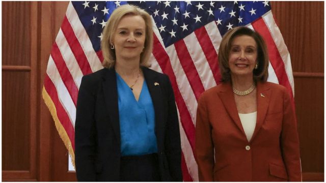 Liz Truss and Nancy Pelosi stand shoulder to shoulder in front of the USA flag