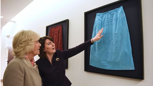 رئيسة كوسوفو السابقة، عاطفة يحيى آغا، تأخذ دوقة كورنوال، كاميلا، في جولة على معرض يظهر تنانير ناجيات من الاغتصاب أثناء الحرب. الصورة التقطت في مارس 2016