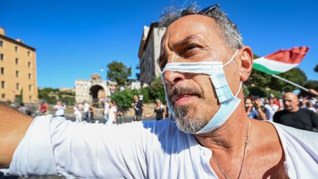 Мужчина в порванной маске на акции протеста против антиковидных ограничений в Риме, сентябрь 2020 года