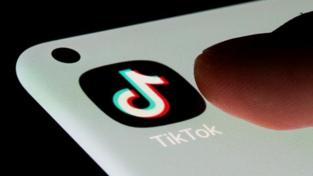 صورة لتطبيق "تيك توك" على هاتف خلوي وإصبع ينقر عليه