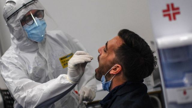 Trabajador de la salud hace la prueba de coronavirus a un viajero en el aeropuerto de Nápoles.