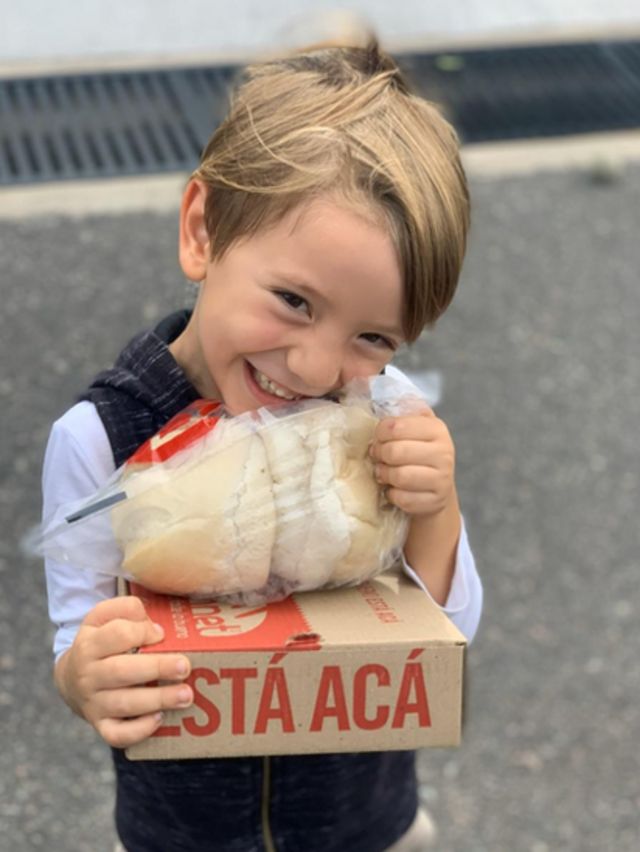 Un niño sostiene una caja con panes.