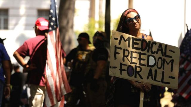 Una mujer en una protesta antivacuna con un cartel que lee "Libertad médica para todos"