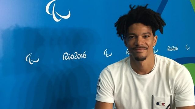 Arnaud Assoumani diante de um cartaz da Rio2016
