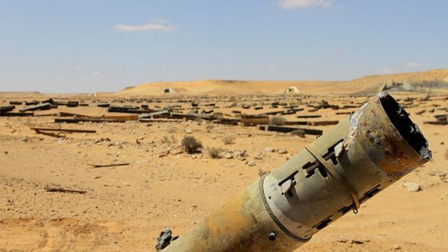 A rocket sticks out in the desert as thousands more weapons are scattered in the distance abandoned by Gaddafi's forces in the desert near Jufra - 2011