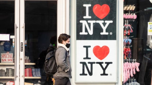 Um homem passa por uma placa que diz: 'Eu amo Nova York'