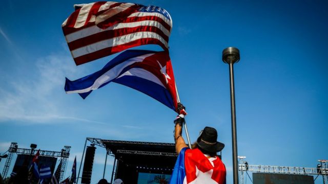 Seseorang mengibarkan bendera Kuba dan Amerika.