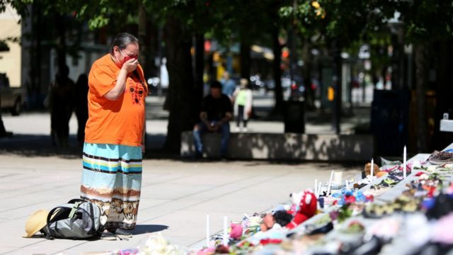 Mulher chora diante de memorial com 215 pares de sapatos infantis do lado de fora da Vancouver Art Gallery, em British Columbia, no Canadá, no dia 29 de maio de 2021