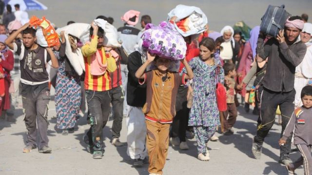 Des familles irakiennes déplacées de la communauté Yazidi traversent la frontière irakienne-syrienne