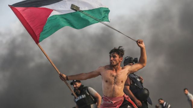 Palestinos lanzan piedras y queman neumáticos en respuesta a las fuerzas israelíes durante una manifestación marítima en la ciudad de Gaza el 22 de octubre de 2018.