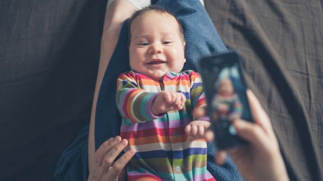 Pessoa fotografa bebê com celular