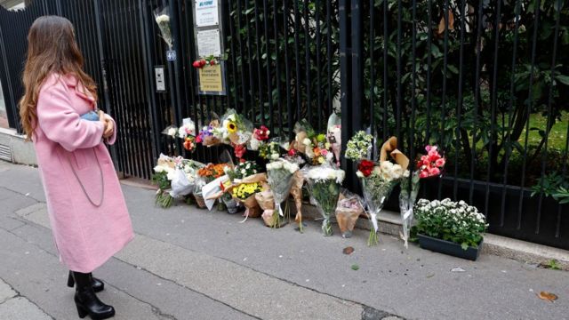 Mulher observa as flores deixadas do lado de fora do prédio onde Lola morava e foi assassinada em 18 de outubro de 2022 em Paris, França