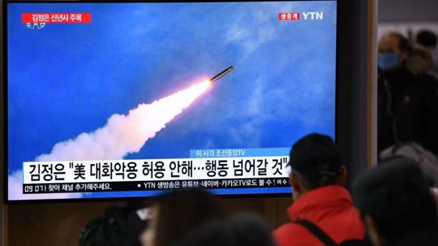 People watch a television news programme showing file footage of North Korea's missile test,