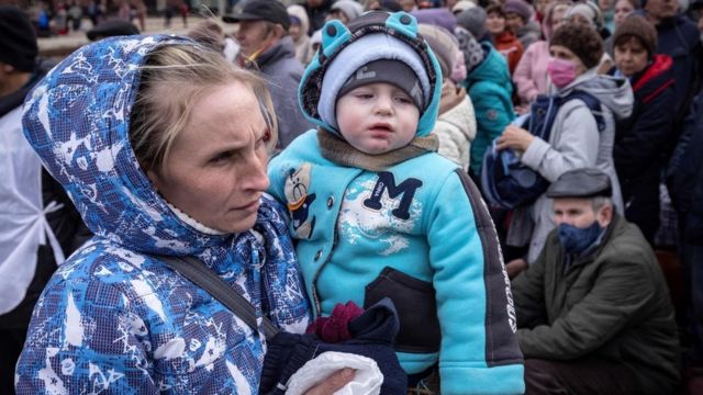 A woman holds a child as families wait to board a train at Kramatorsk central station as they flee the eastern city of Kramatorsk, in the Donbass region o­n April 5, 2022
