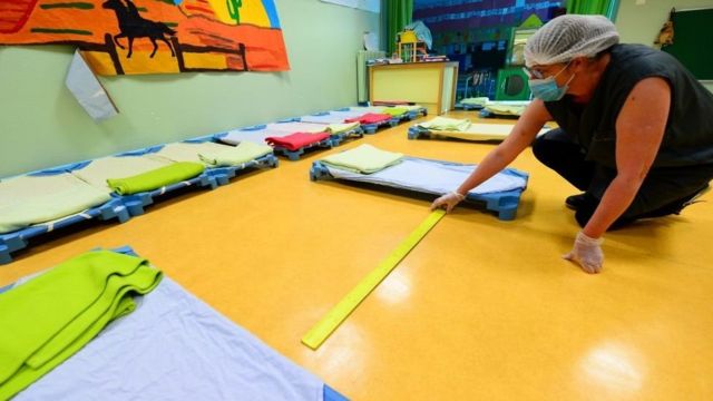 Staff member at a French pre-school measure the spaces between sleeping mats