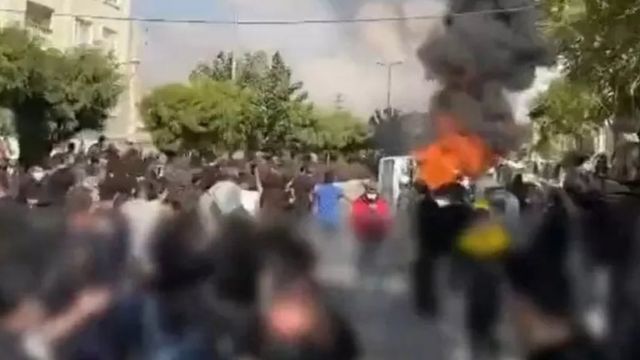 Screenshot from a video clip published by opposition activists showing protesters near a burning vehicle in the Karaj region, west of the Iranian capital, Tehran