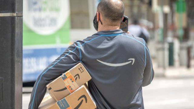 Un trabajador de Amazon, de espaldas, con unos paquetes