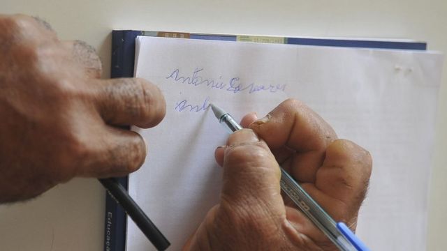 Homem escrevendo o nome em um papel