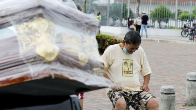Un familiar de una víctima de coronavirus llora junto al ataúd que es transportado en una camioneta el 4 de abril de 2020 en Guayaquil, Ecuador.