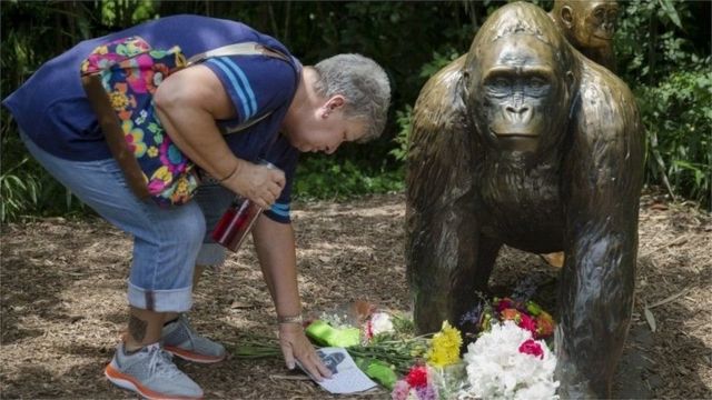 Una mujer le pone flores a una estatua de Harambe