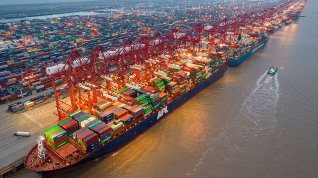 Porto de Xangai em vista aérea, com um grande navio cargueiro cheio de containers atracado