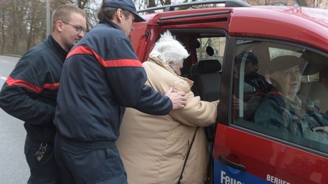Des sapeurs pompiers Allemands évacuant des personnes âgées