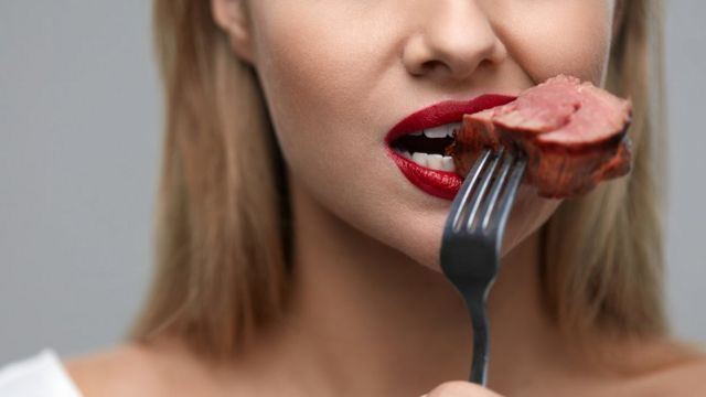Una mujer con un trozo de carne en la boca.