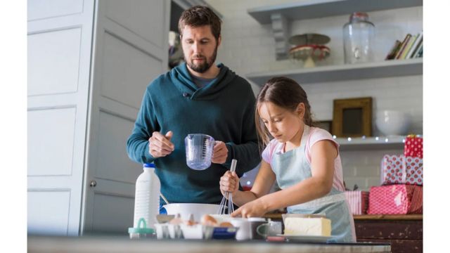 A girl prepares food in the kitchen with her father