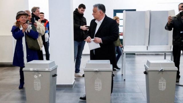 Orban holds a ballot paper in front of the ballot box