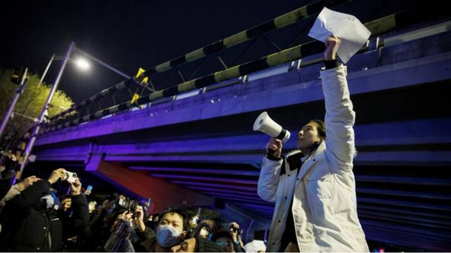 11月28日，在北京，在为乌鲁木齐火灾受害者守夜后，一名男子拿着白纸抗议当局的疫情封控措施。