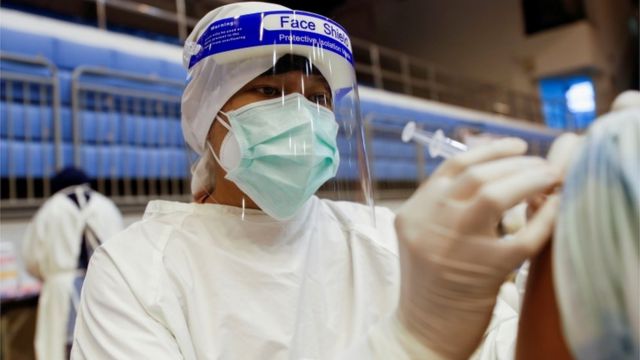 Perawat Thailand menyuntikkan vaksin ke lengan pasien.