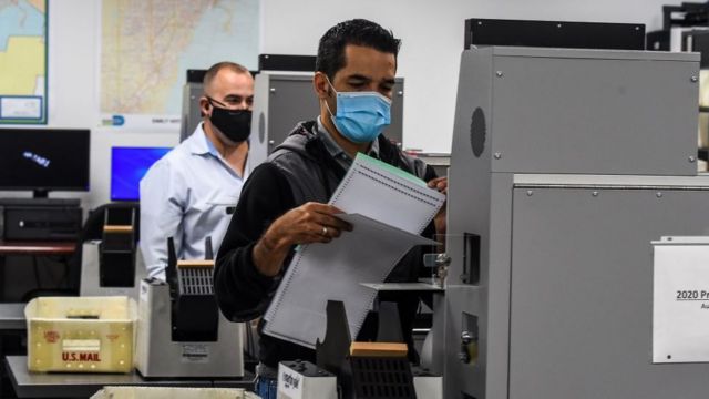 Employees of Miami-Dade Elections Department scan the votes for counting during Florida primaries amid the pandemic