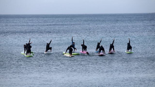 People exercise on paddle boards in the sea at a beach near Athens